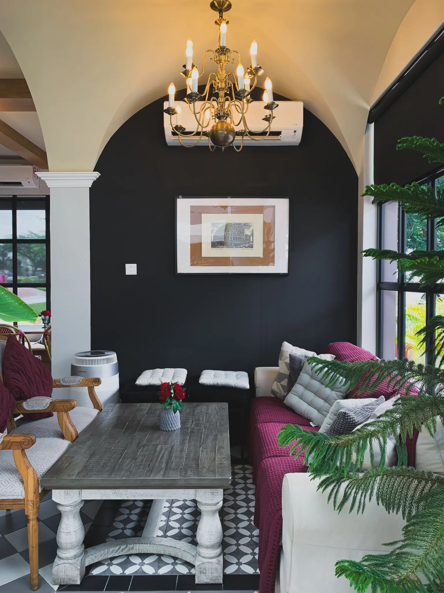 Black arched accent wall behind a bright sitting area beneath a brass chandelier