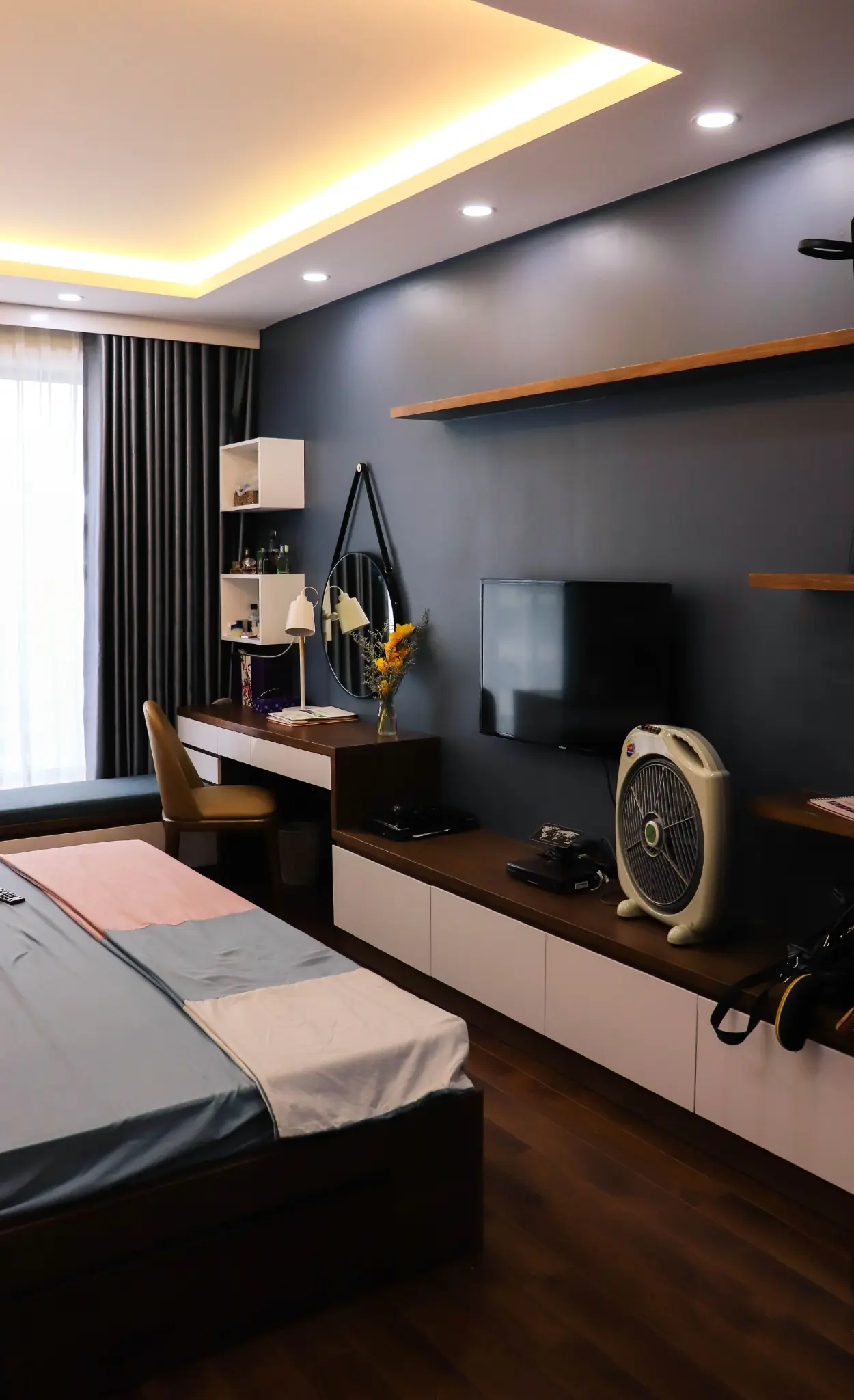 Matte black bedroom wall behind a television and compact desk